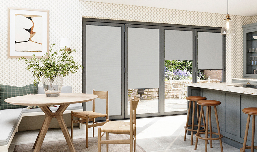 A bright modern kitchen-diner with grey roller blinds fitted to large bifold doors